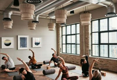 Spacious yoga and wellness studio with industrial ceilings and large windows.