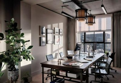 Sunlit professional office suite with long wooden desks and framed wall art.