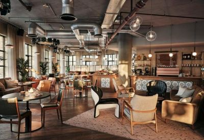 Industrial-style lounge and café area with eclectic seating and exposed ductwork.