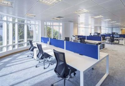 Bright open-plan office space with blue privacy screens and ergonomic black chairs.