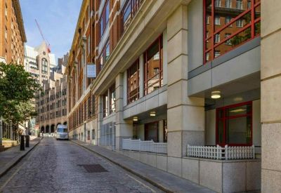 Cobblestone street leading past a modern office building with red-framed windows.