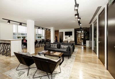 Modern lounge area with leather armchairs, wooden flooring, and track lighting.