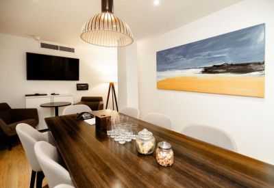 Intimate meeting room with a dark wood table, designer pendant light, and beach artwork.