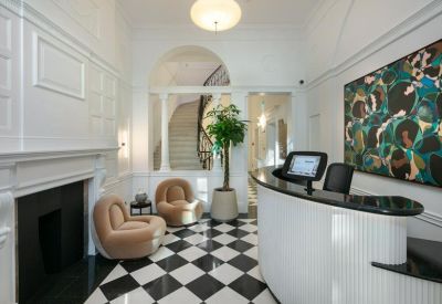 Elegant reception area with a curved white desk, checkered floor, and a marble fireplace.