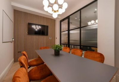 Professional meeting room with a grey table, orange chairs, wood-slat feature wall, and glass partition.