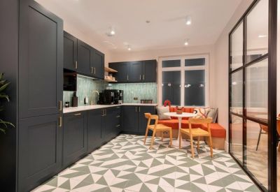 Modern kitchen and dining area featuring dark cabinetry, geometric tiles, and orange banquette seating.