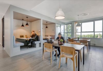 Lounge area with private work booths, wooden dining tables, and pendant lighting.