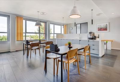 Modern kitchen and dining area with grey cabinetry and wooden chairs.