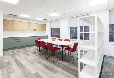 Sunlit dining area with red seating and a large white communal table.