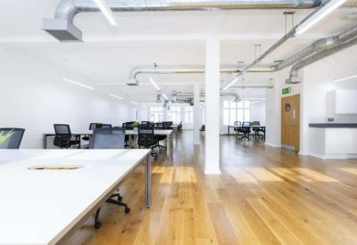 Bright open-plan workspace with wooden floors and industrial exposed ductwork.