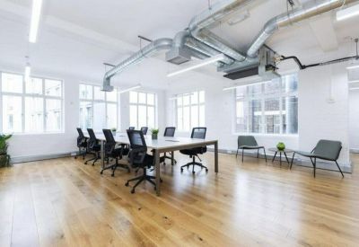 Modern meeting room with a large table, black mesh chairs, and overhead pipes.