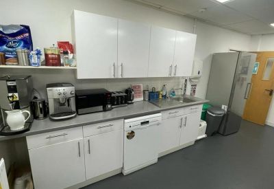 Bright office kitchen with white cabinetry, modern appliances, and a dedicated coffee station.