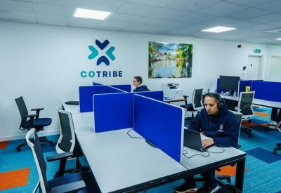 Open-plan workspace with white desks, blue privacy screens, and colorful carpet flooring.