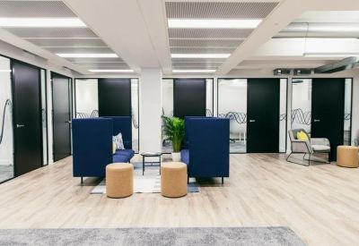 Communal breakout area with navy high-back booths and tan stools.