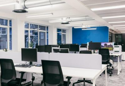 Open-plan office with white desks, ergonomic chairs, and a blue feature wall.