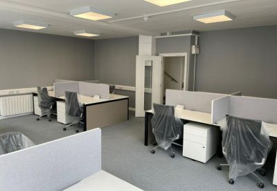 Professional workspace with rows of desks, privacy screens, and white storage pedestals.