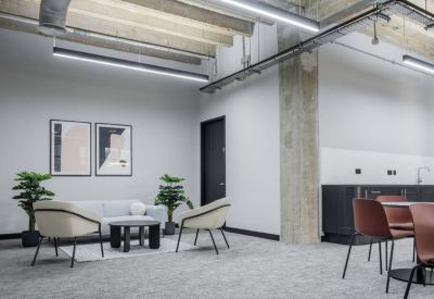 Bright lounge area with grey sofa, cream armchairs, and framed wall art.