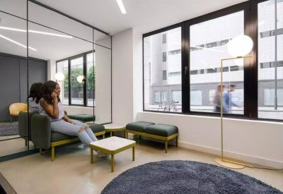 Well-lit waiting area with green cushioned benches and a large circular rug.
