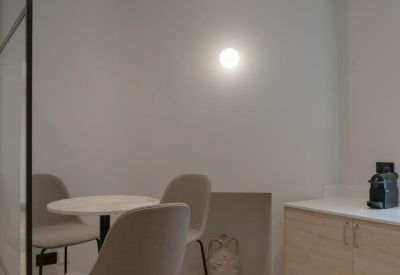 Breakout area with high stools, a marble table, and a small kitchenette unit.