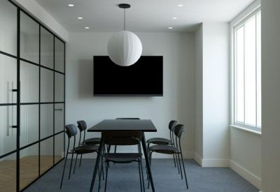 Professional meeting room with a dark table, black chairs, and a glass partition wall.