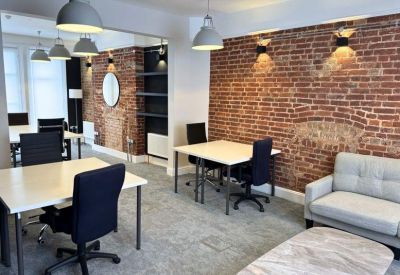 Bright coworking area with a red brick feature wall and industrial-style pendant lighting.