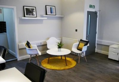 Small meeting room with white chairs, a round table, and a yellow area rug.