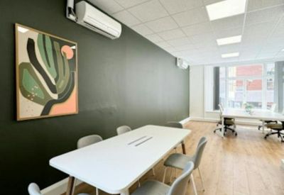Meeting room with a white table, grey chairs, and a dark feature wall with abstract art.