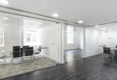 Two glass-walled meeting rooms with black chairs and dark wood flooring.