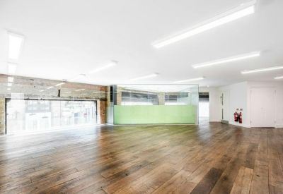 Sunlit office area with high ceilings, exposed brick details, and polished timber floors.
