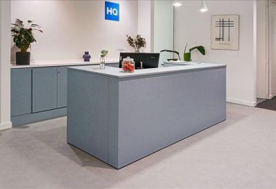 Bright reception desk with blue cabinetry, plants, and HQ branding.