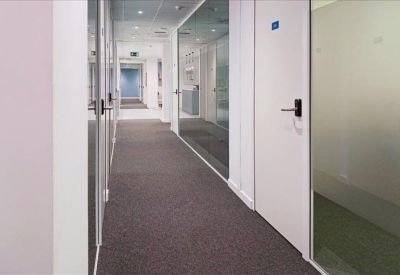 Long office corridor with glass partitions and white doors.