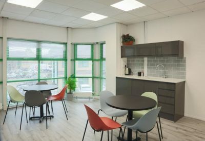 Office kitchen and break area with grey cabinetry and colorful dining chairs.
