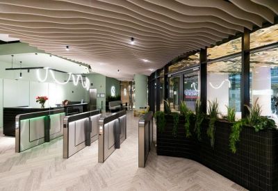 Modern reception lobby featuring security turnstiles, a curved planter, and a wavy architectural ceiling.