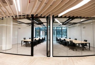 Bright workspace featuring two long wooden communal tables separated by glass partitioning.