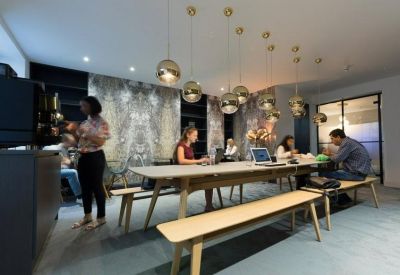 Communal dining area with long wooden tables and gold globe pendant lights.