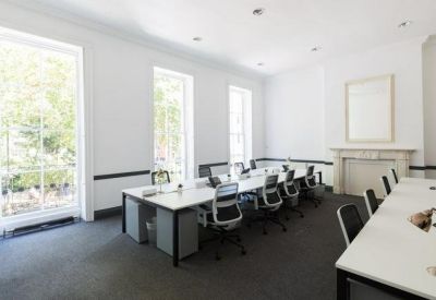 Bright open-plan workspace with multiple white desks and large windows.