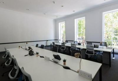 Meeting room with long white tables, ergonomic chairs, and garden views.