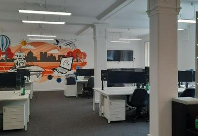 Open-plan office space featuring a colorful city mural and rows of modern workstations.
