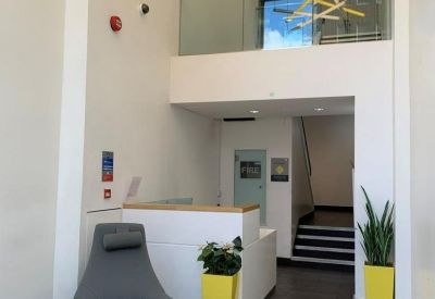 Reception area with a grey armchair, yellow planters, and a mezzanine level.