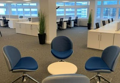 Informal meeting area with four blue swivel chairs arranged around a small white table.