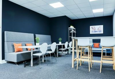 Breakout space with grey high-back sofas, white tables, and navy blue walls.