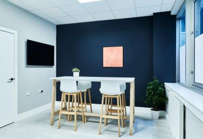 High-top meeting table with white stools set against a dark blue feature wall.