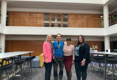 Staff members standing in a bright, multi-level atrium lobby.