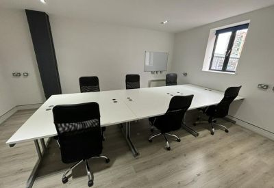Meeting room with a long white conference table, black ergonomic chairs, and a whiteboard.