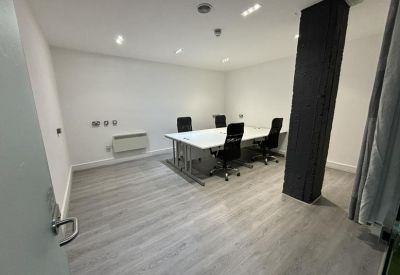 Small conference room with a white table, grey accent pillar, and wood-style flooring.