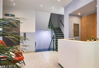 Bright reception area featuring a curved white desk and orange accent armchairs.