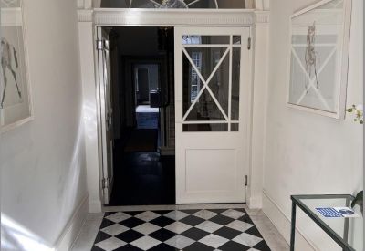 Elegant entrance hallway with black and white checkered marble flooring and arched doorway.