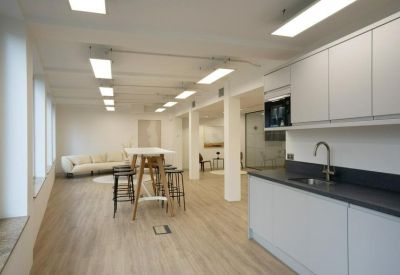 Bright kitchen and breakout area with wooden floors and high stools.