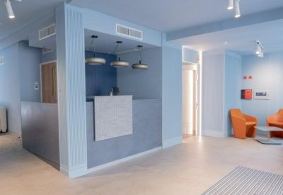 Sleek blue reception area with orange armchairs and a grey desk.
