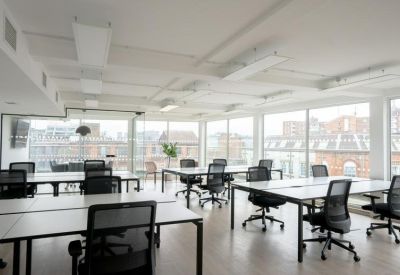 Spacious open-plan office with white desks and large windows.